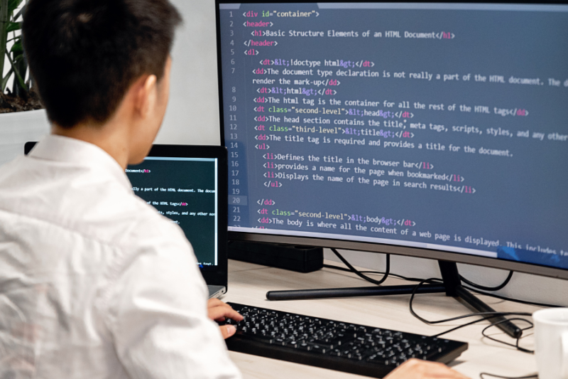 Student zit achter computer met html-code op het beeldscherm